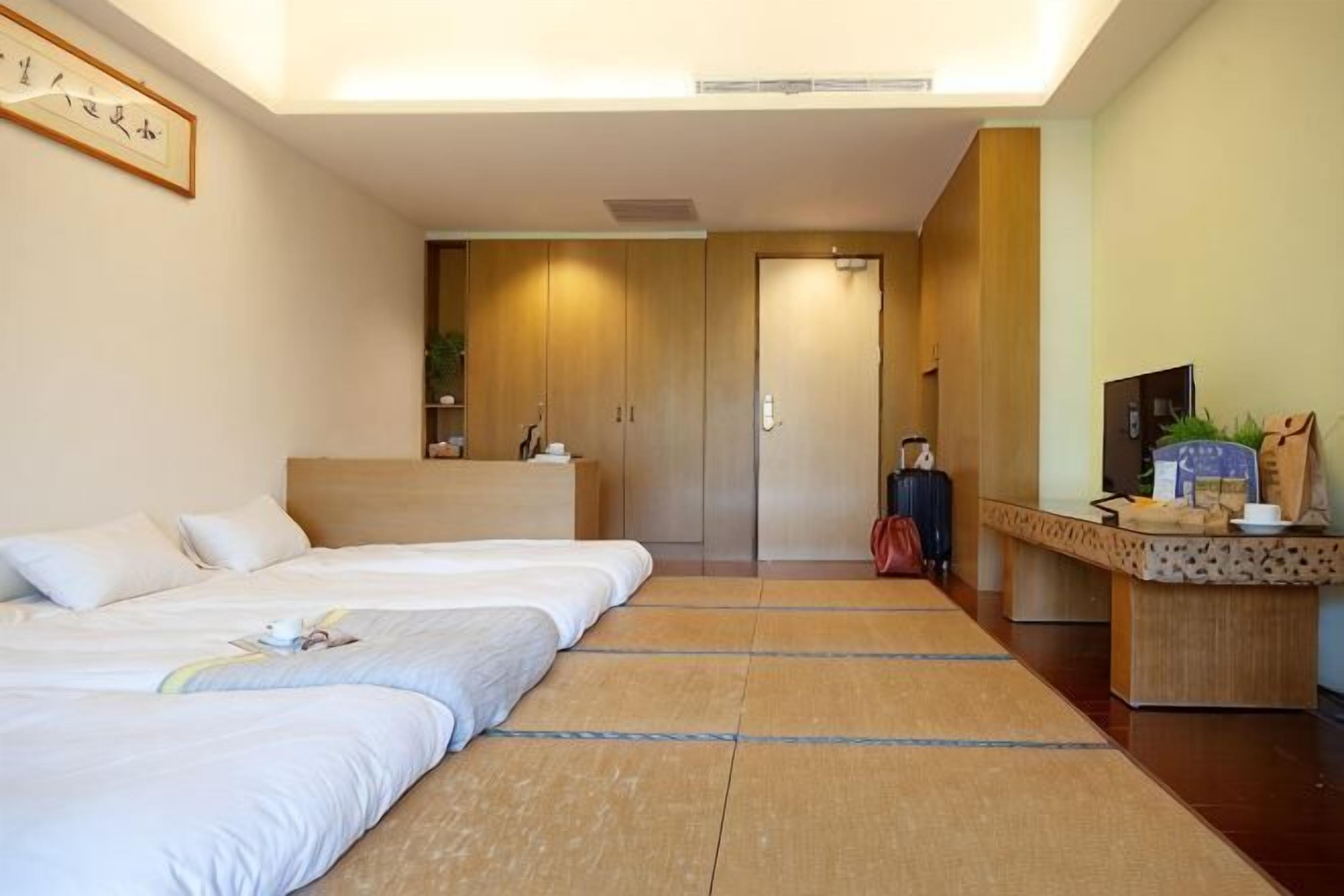 A hotel room with a bed, a desk, a TV, and a door.