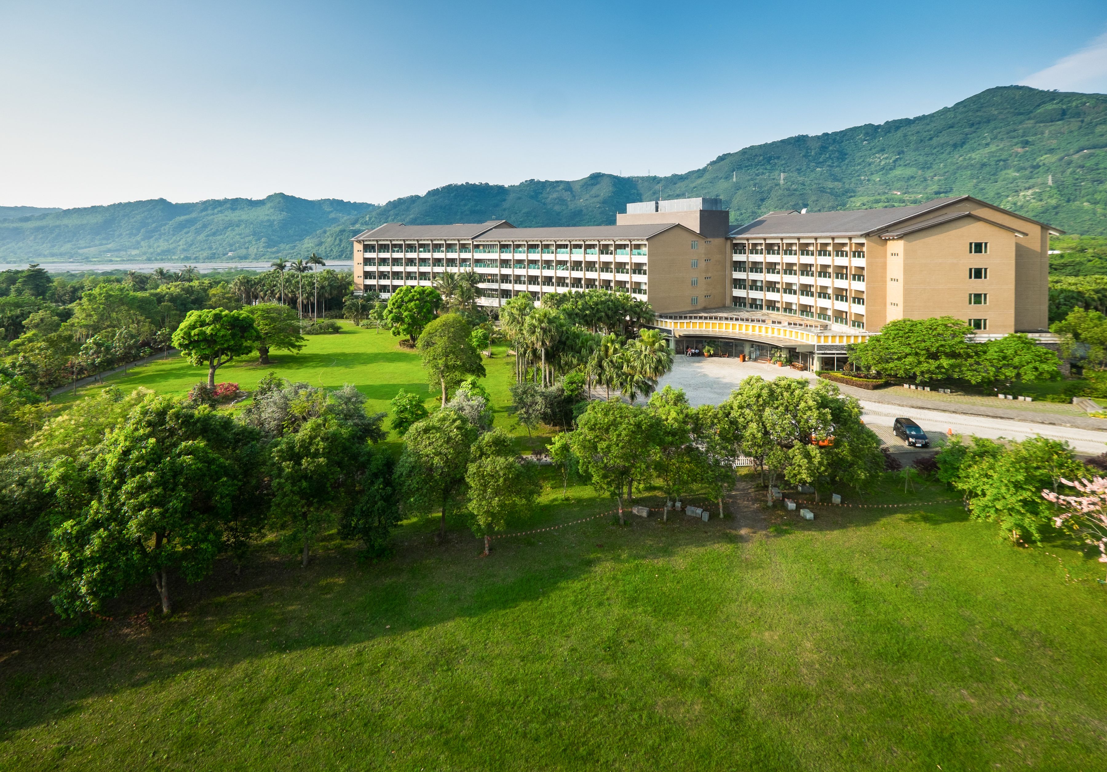 Un gran hotel de varios pisos, rodeado de exuberante vegetación y un paisaje montañoso.