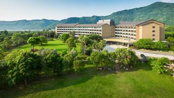 Un gran hotel de varios pisos, rodeado de exuberante vegetación y un paisaje montañoso.