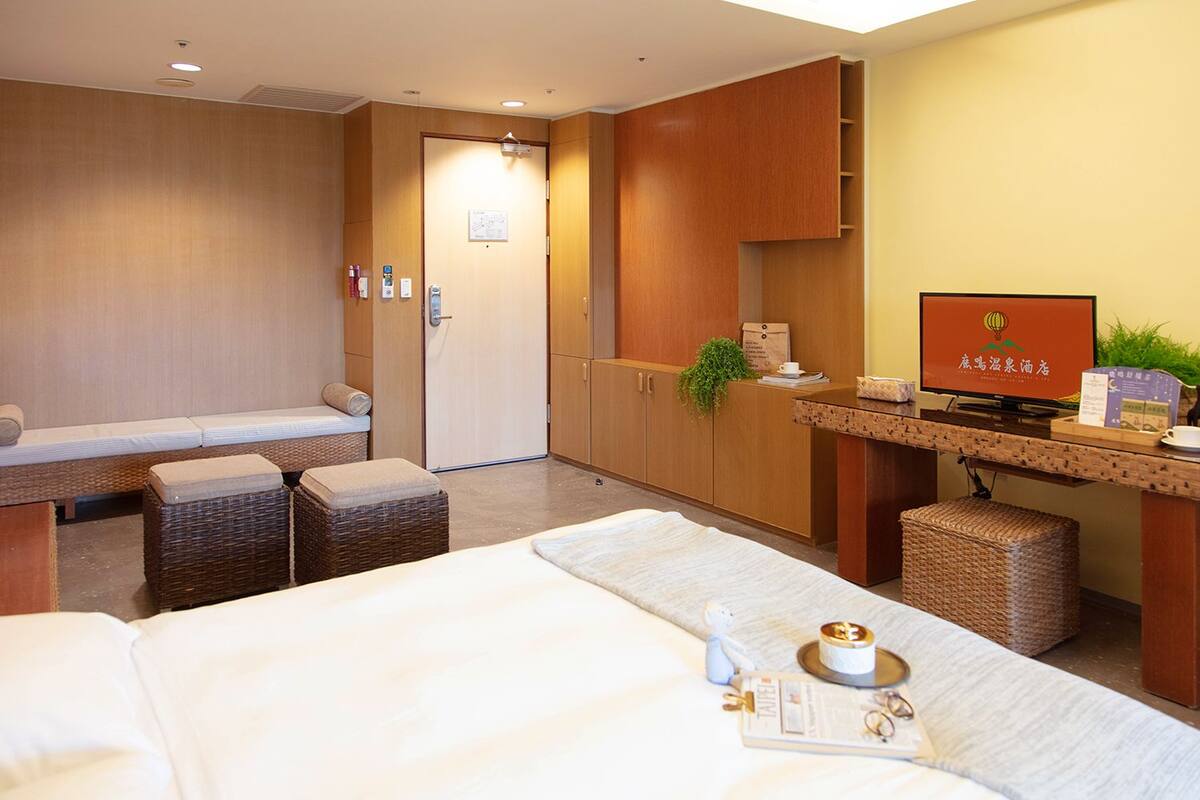 Habitació d'hotel amb llit, escriptori i zona de recepció.