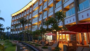 A multi-story hotel with a curved facade, outdoor seating area, and a water feature. - Luminous Hot Spring & Resort (Luye)
