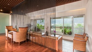 A modern interior with wicker furniture, a wooden ceiling, and large windows offering a view of greenery. - Luminous Hot Spring & Resort (Luye)
