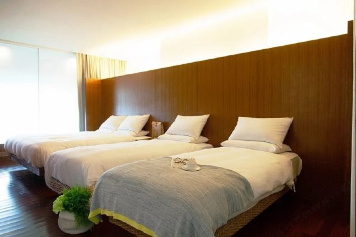 A hotel room with two beds, a large window, and a wooden headboard.