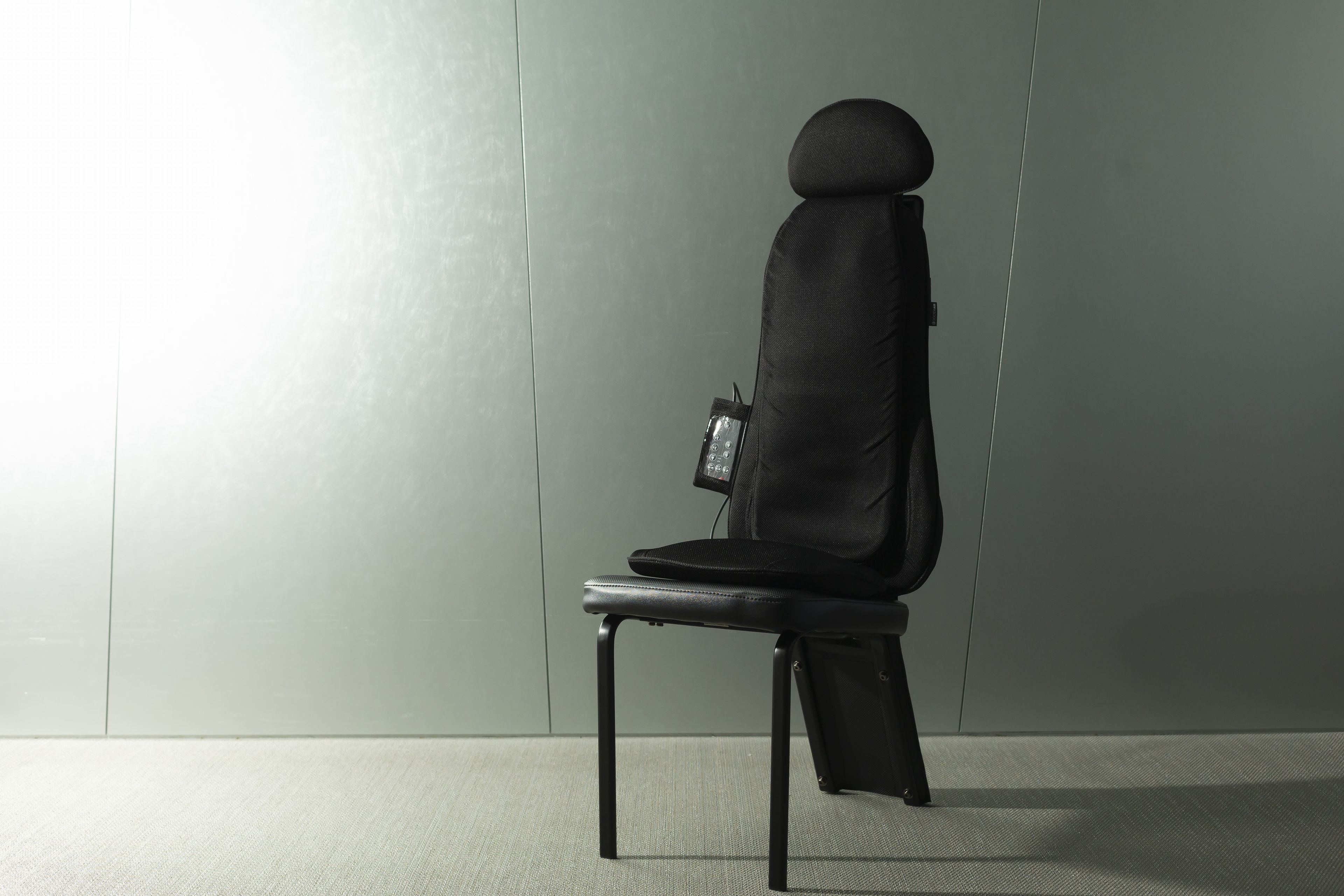 Una silla moderna con respaldo alto y asiento pequeño, colocada frente a una pared lisa.