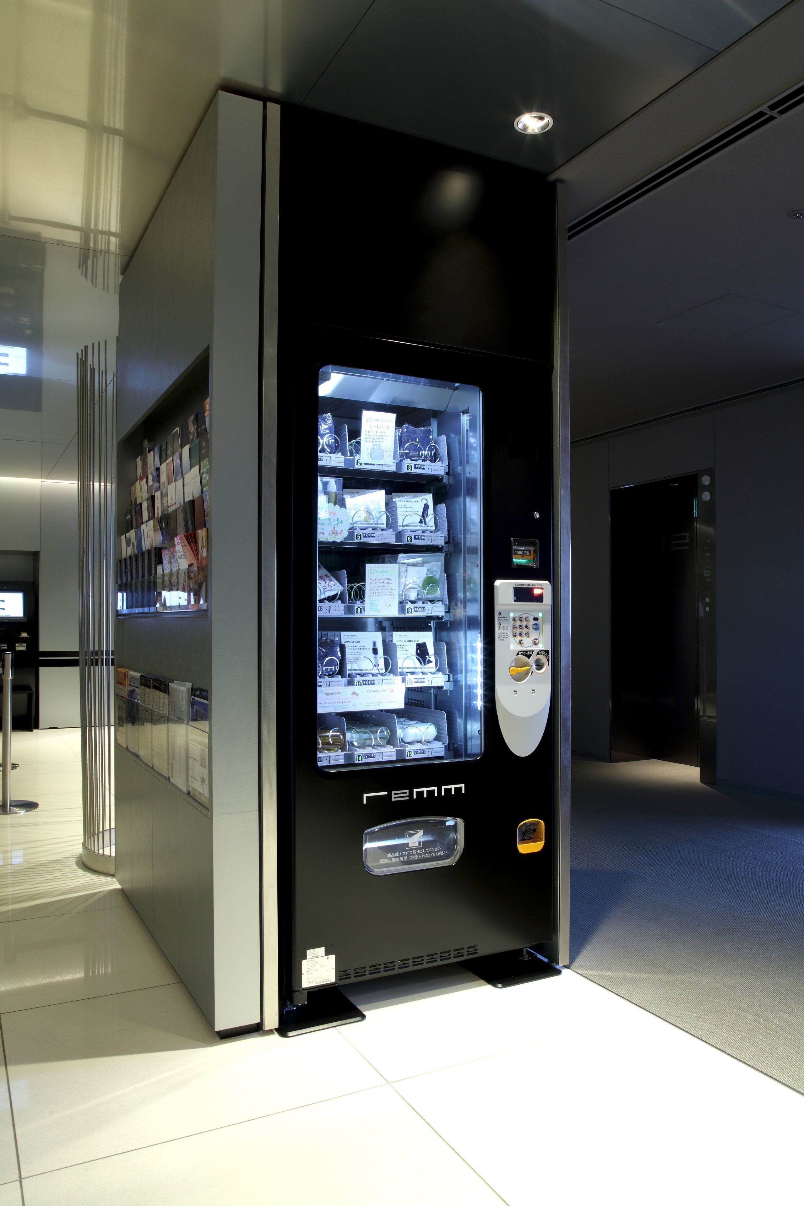 A vending machine with a digital display and a keypad, located in a modern indoor setting.