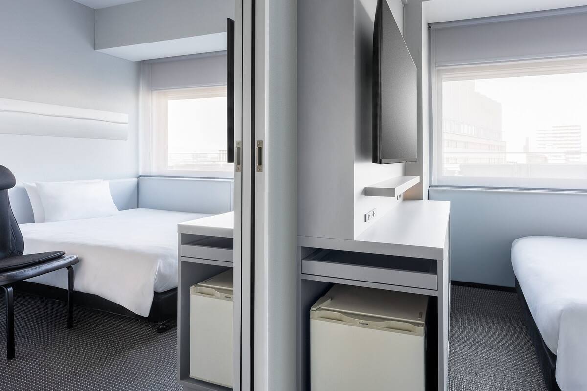 A hotel room with a bed, desk, chair, and a television.