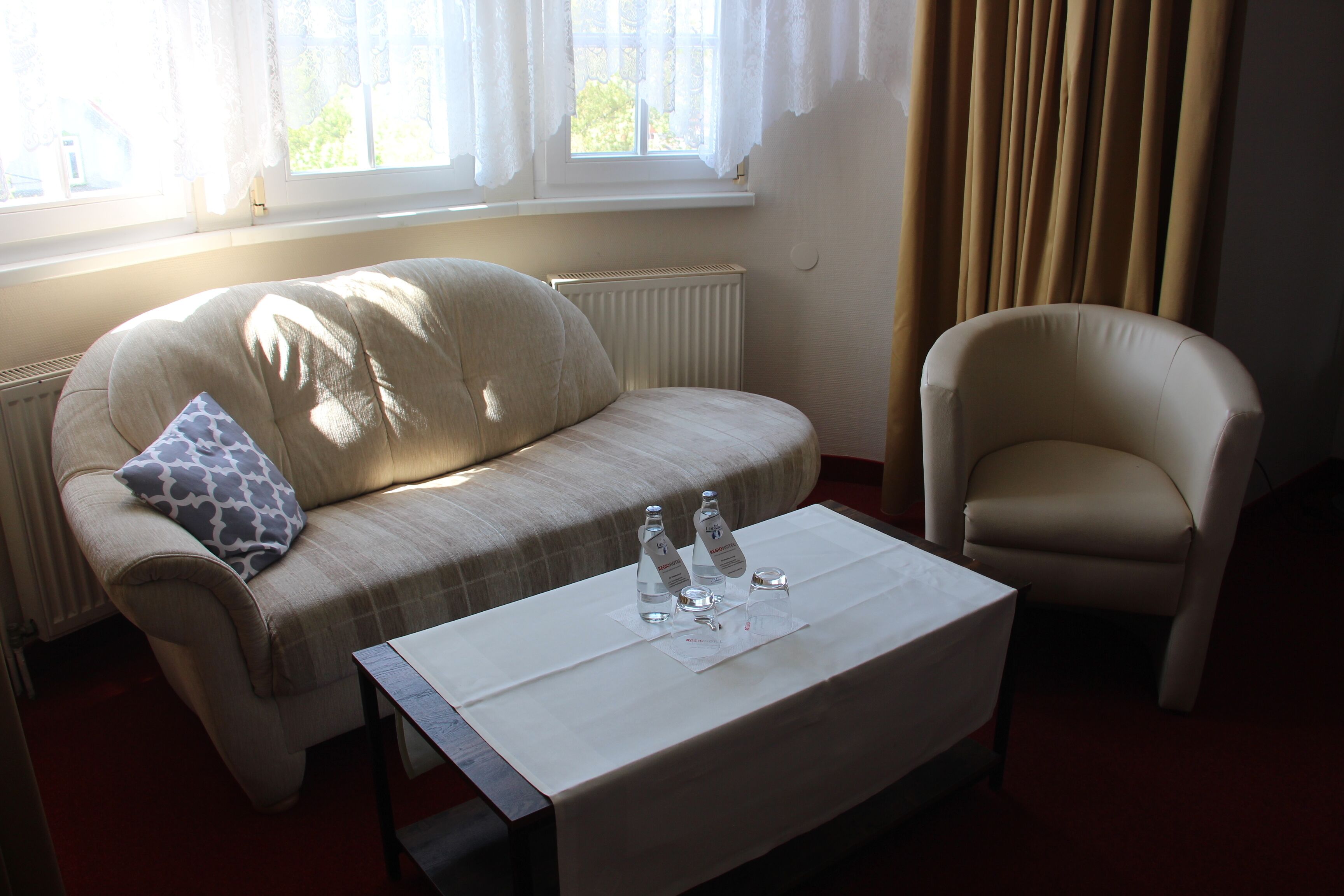 Ein Wohnzimmer mit einer Couch, einem Sessel und einem Couchtisch mit Wasserflaschen und Gläsern.