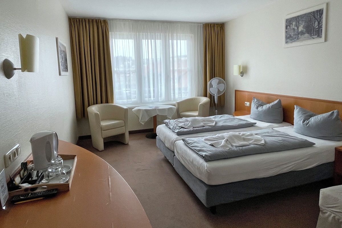 Une chambre d’hôtel équipée d’un lit, d’un bureau, d’une chaise, d’une table et d’un ventilateur.