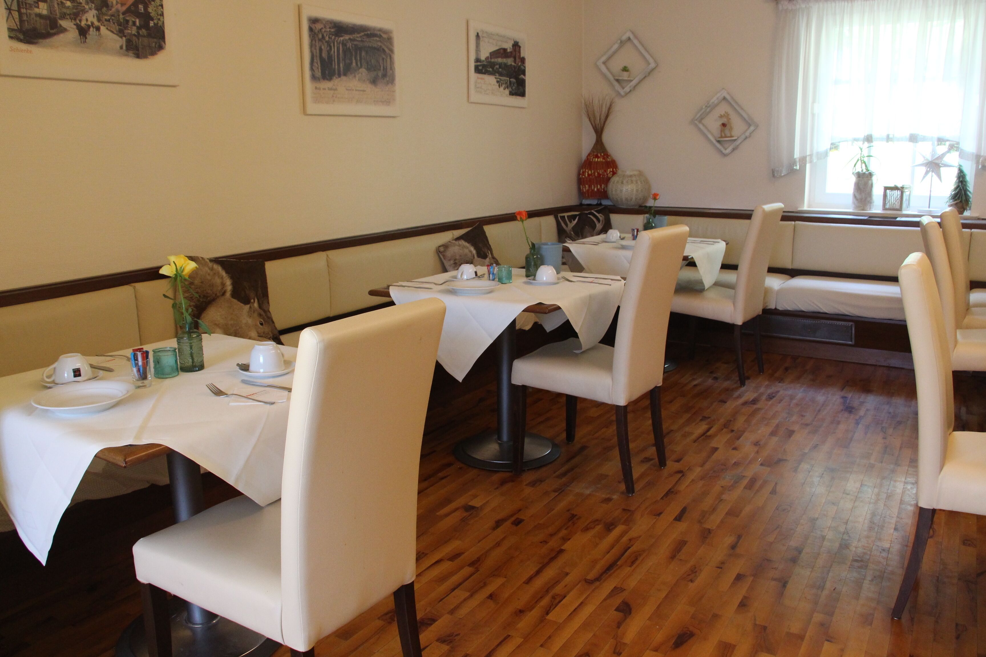 Un espace repas avec des tables disposées pour accueillir quatre personnes, un plancher en bois et une fenêtre offrant une vue agréable.