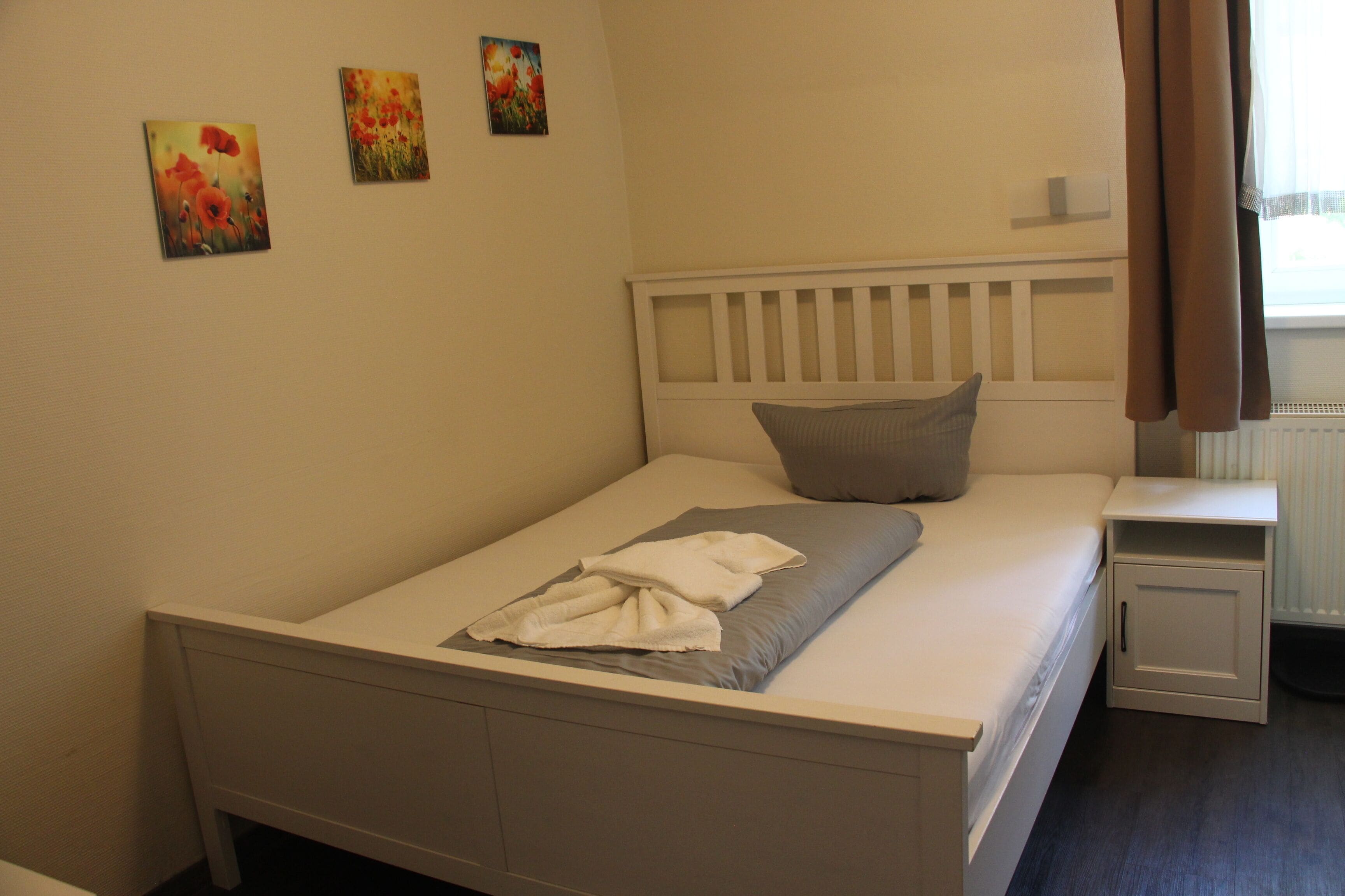 Un dormitorio con una cama individual, una mesita de noche y tres cuadros colgados en la pared.