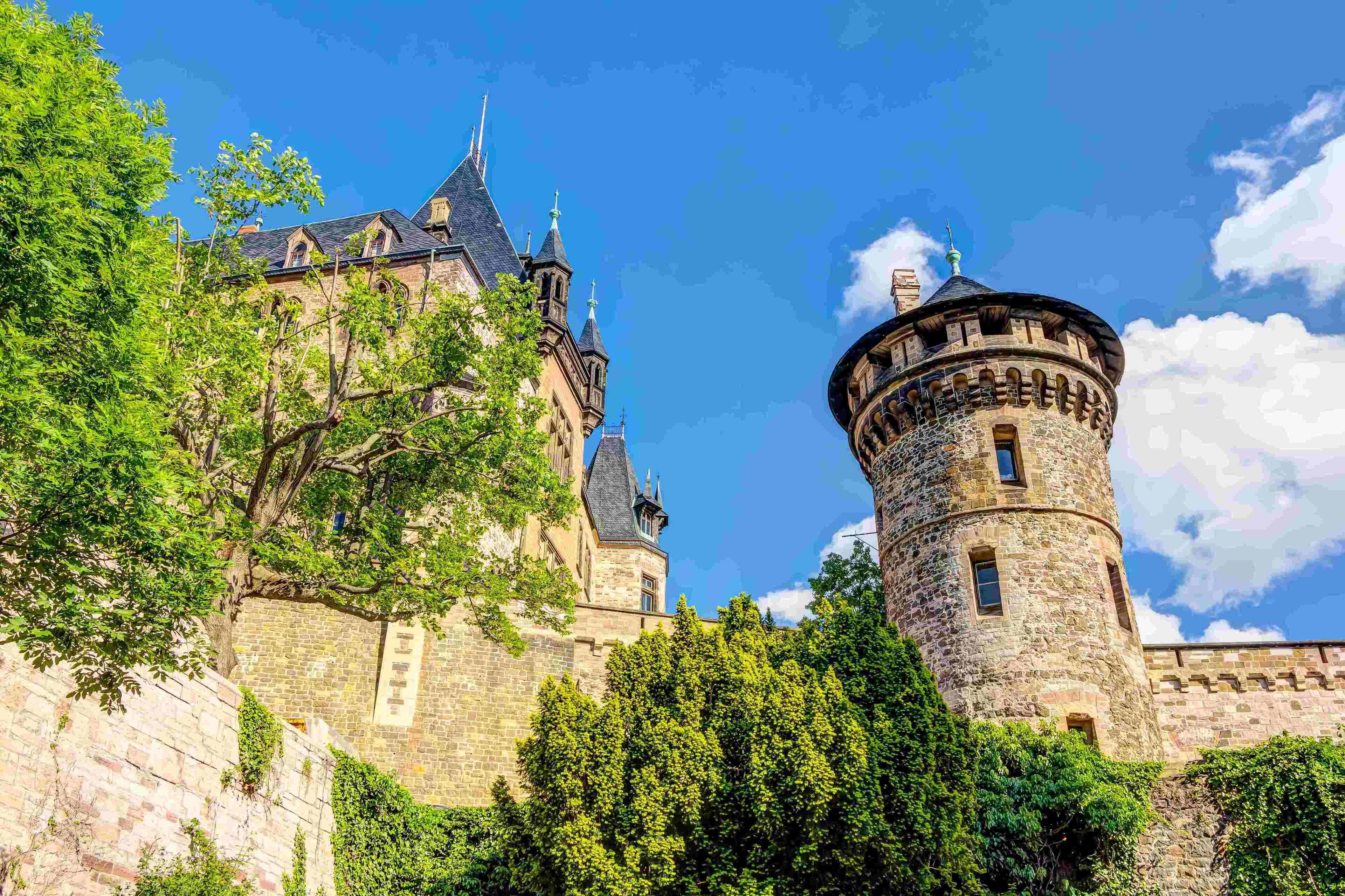 A historic castle with a prominent tower and a large building with multiple towers.
