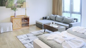 Una habitación de hotel moderna con sofá, cama, escritorio y un ventanal grande.