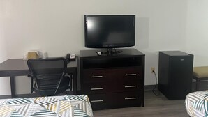 A hotel room with a bed, a desk with a computer, a television, a small cabinet, and a black speaker. - Motel 6 – Spindale, NC – Forest City (Spindale)