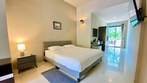 Un dormitorio moderno con una cama grande, mesitas de noche, un televisor de pantalla plana montado en la pared y vistas al exterior a través de un ventanal.