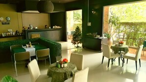 Un restaurante con pared verde, una recepción y mesas con sillas.