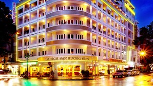 Un hotel de varios pisos con fachada curva, múltiples balcones y un restaurante a nivel de calle.