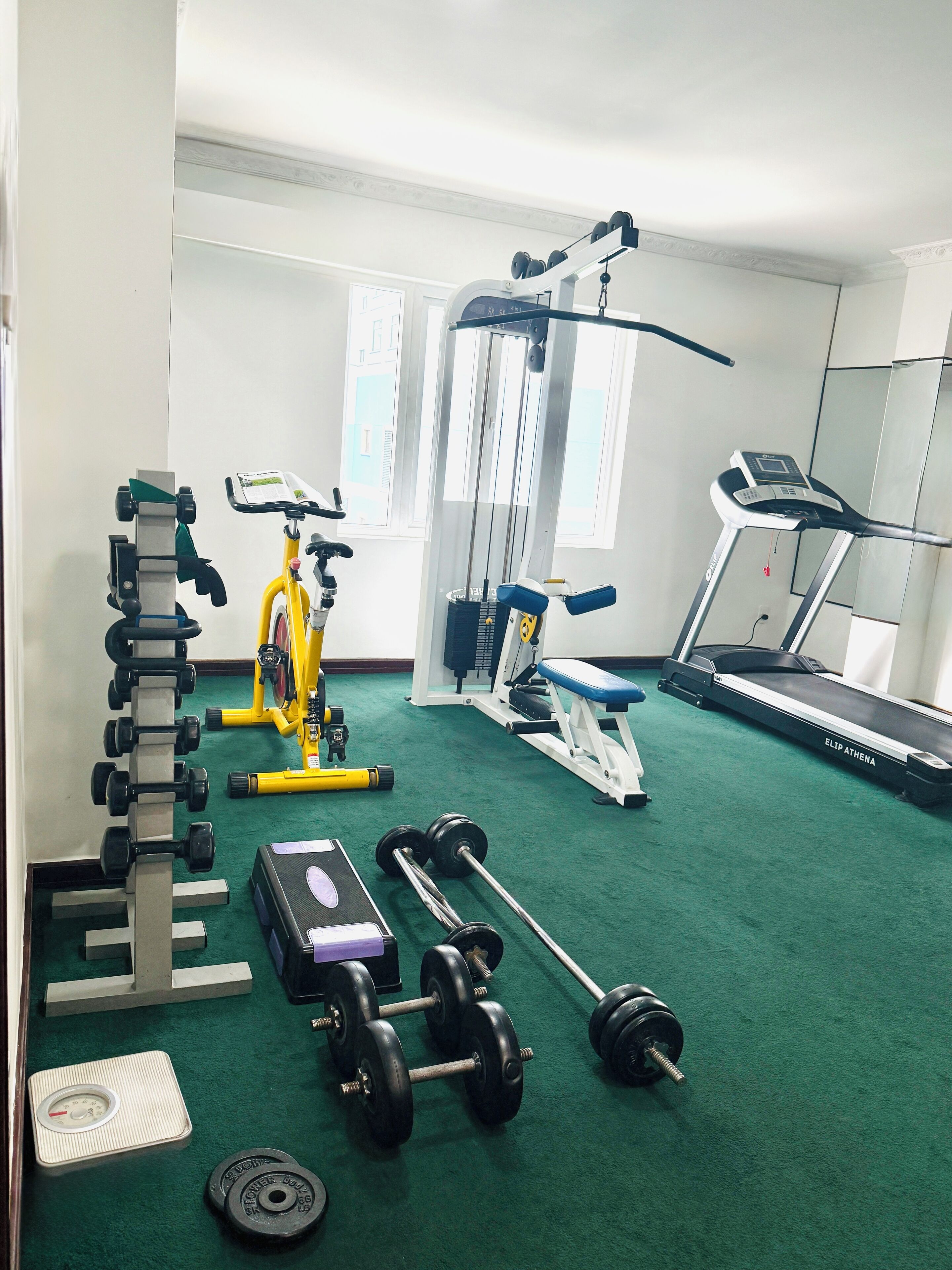 A gym with exercise equipment including dumbbells, a bench, and a treadmill.