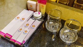 Un plan de travail sur lequel sont disposés des articles de toilette, notamment un plateau contenant des cotons-tiges, un petit récipient et deux verres.