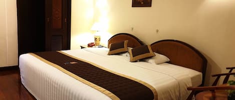 Ein Hotelzimmer mit einem großen Bett, einem Nachttisch mit Lampe, einem Sessel und einem kleinen Tisch mit Pflanze.
