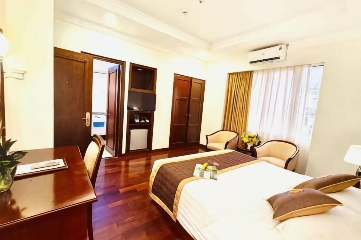 Una habitación de hotel con cama, escritorio, silla, televisor y armario.
