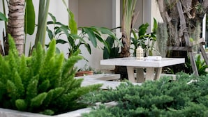 A garden with a concrete table, potted plants, and a small house model.