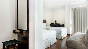 A hotel room with two beds, a small table, a sofa, and a mirror.