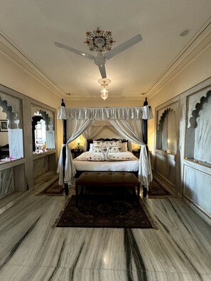 Restful retreat with a large bed, ornate wall panels, and a ceiling fan.