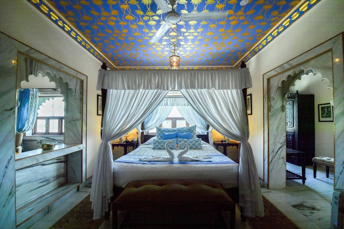 A bedroom with a canopy bed, a ceiling fan, and a chandelier.