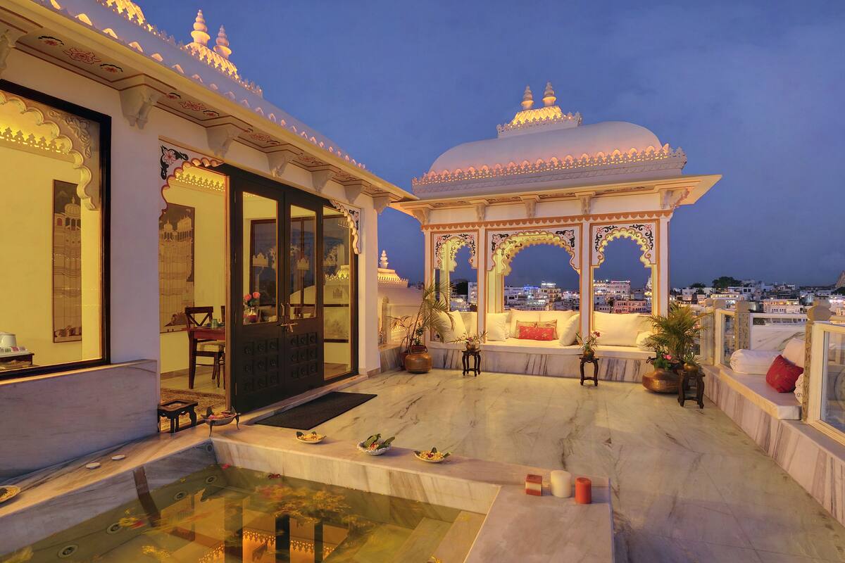 A well-lit outdoor area with a seating arrangement, a small pool, and a view of the cityscape in the background.
