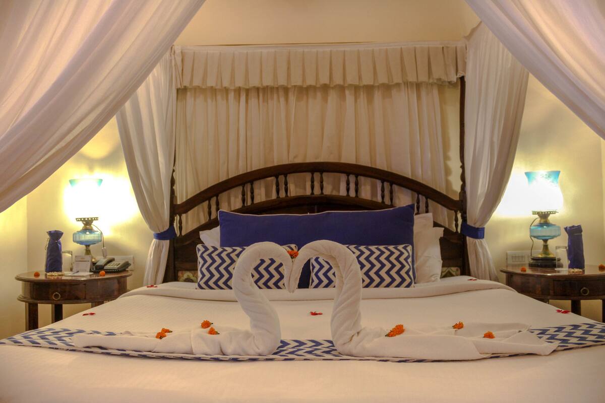 A bed with a canopy, a blue pillow, and a wooden headboard.