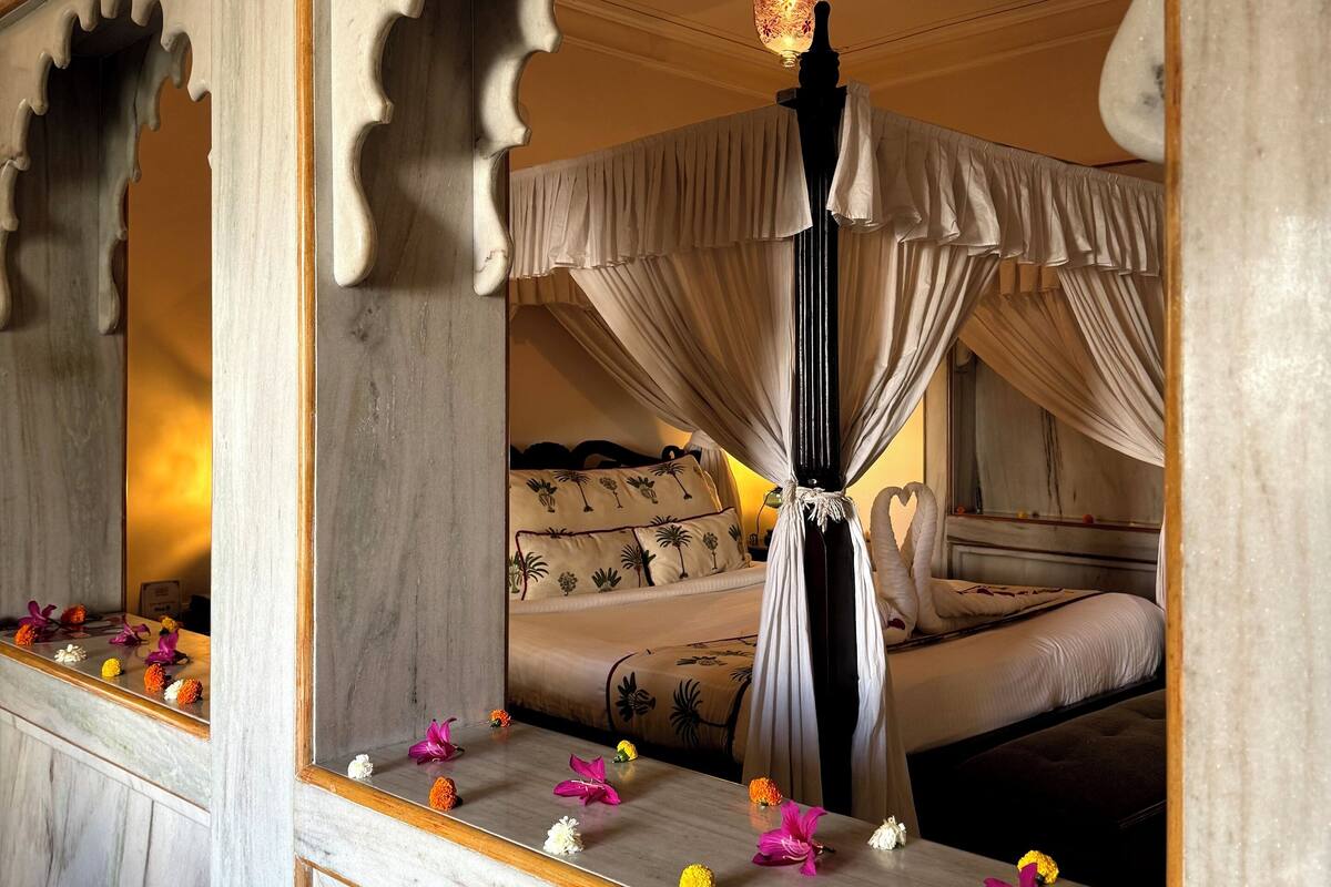 A room with a bed, a mirror, and a decorative ceiling light.