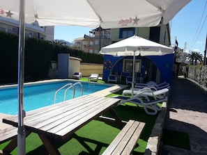 Una piscina al aire libre de temporada, sillones reclinables de piscina