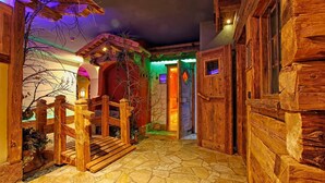 A rustic wooden building with a stone-tiled entrance and a wooden gate. - Hotel Arnika Wellness (Moena)