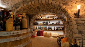 A wine cellar with wooden barrels and shelves of wine bottles. - Hotel Arnika Wellness (Moena)