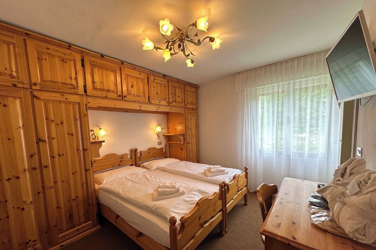 A wooden room with two beds, a desk, and a TV.