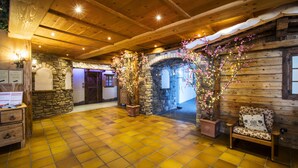 A wooden interior with a checkered floor, stone walls, and a bench. - Hotel Arnika Wellness (Moena)