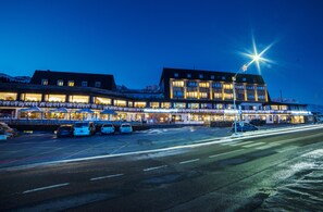 Un hôtel à plusieurs étages, avec des fenêtres illuminées et un grand éclairage en forme d’étoile sur le toit.