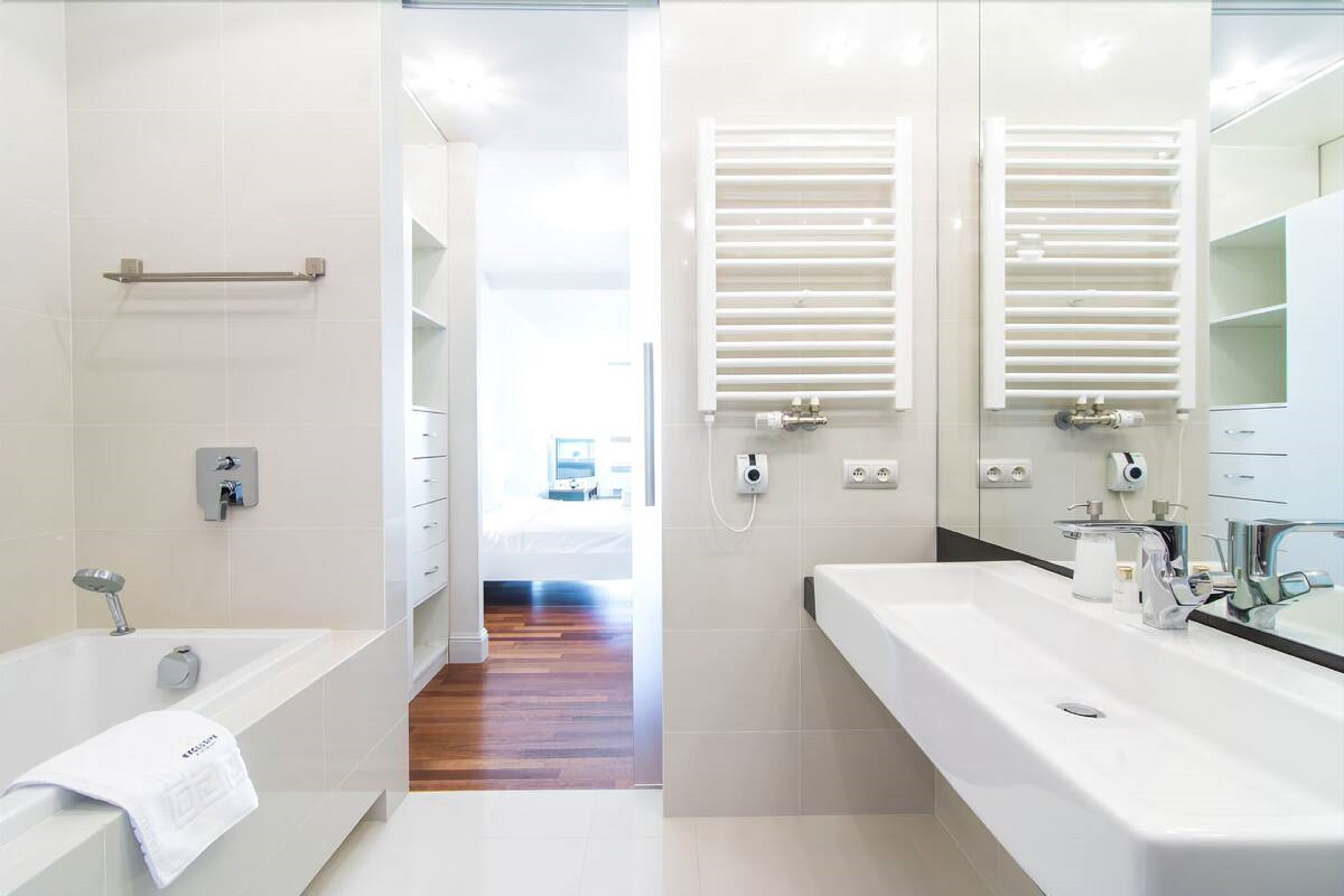 A modern bathroom with a bathtub, a large sink, and two towel racks.