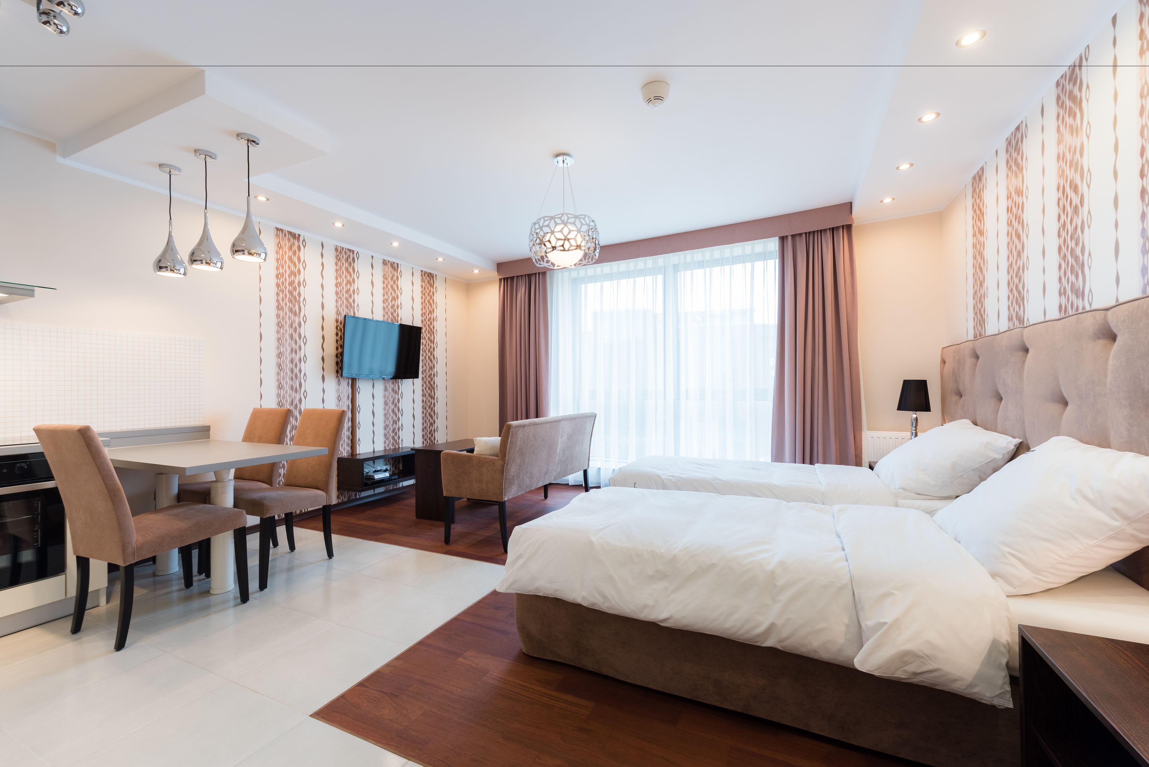 Ein modernes Hotelzimmer mit Essbereich, Fernseher und einem großen Bett.