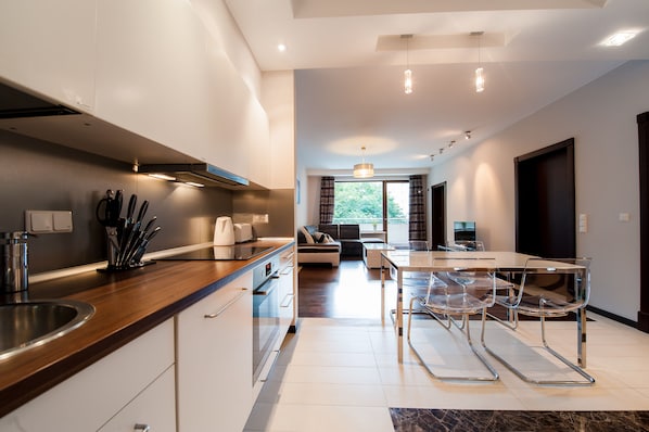 A modern kitchen with stainless steel appliances, a wooden countertop, and a dining area with a glass table and chairs. - Exclusive Apartments Warsaw City Centre (Warsaw)