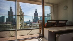 Ein Balkon mit Blick auf eine Stadtlandschaft, darunter ein markantes Gebäude mit einem Turm.