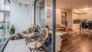A modern living room with a glass partition, wicker furniture, and a dining area with a kitchen in the background. - Exclusive Apartments Warsaw City Centre (Warsaw)