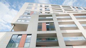 A modern building with a glass facade, a red door, and multiple floors. - Exclusive Apartments Warsaw City Centre (Warsaw)