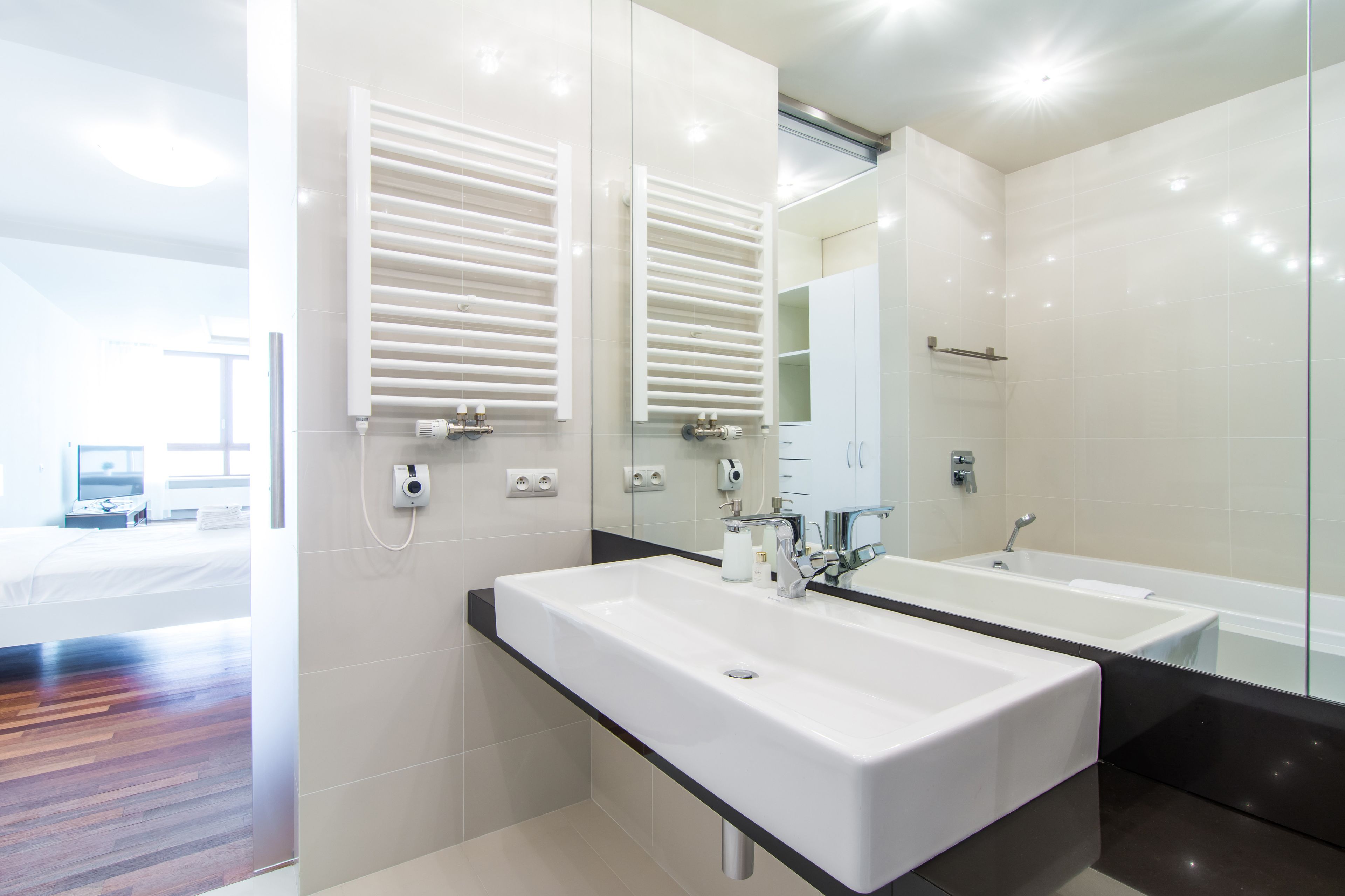 A modern bathroom with two sinks, a large mirror, and a glass shower enclosure.