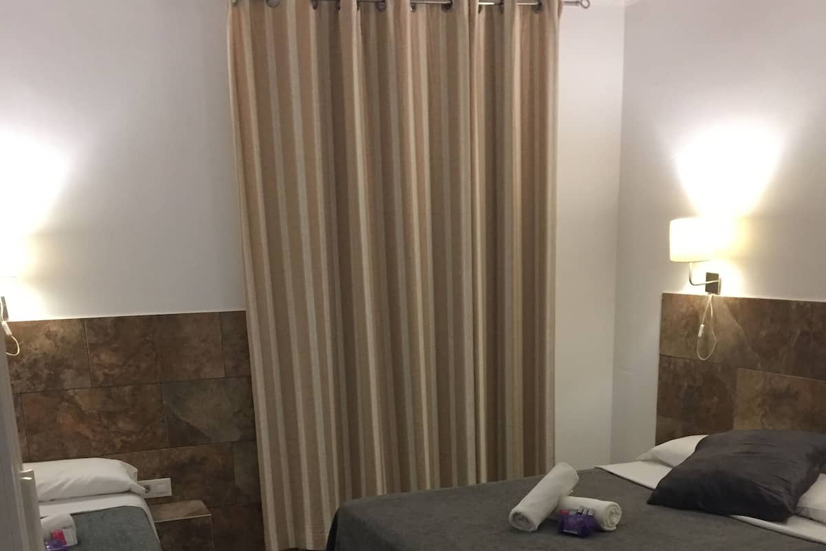 Habitación de hotel con dos camas, baño y zona de ducha.