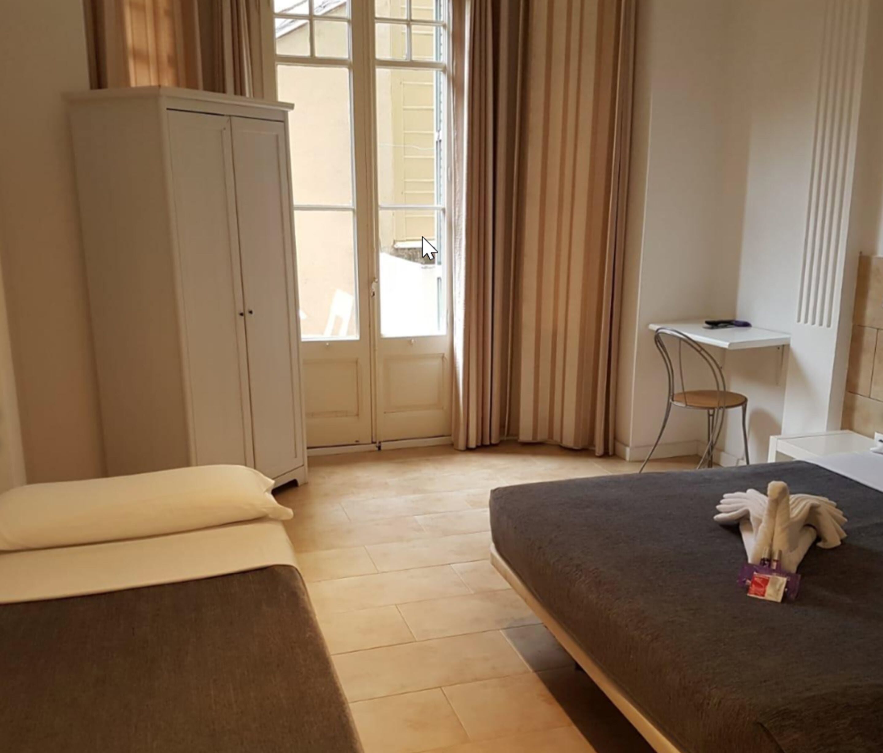 Habitación de hotel con dos camas, un escritorio y un armario.