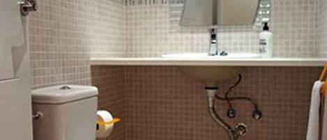 Un bagno con il water, un lavandino e uno specchio.
