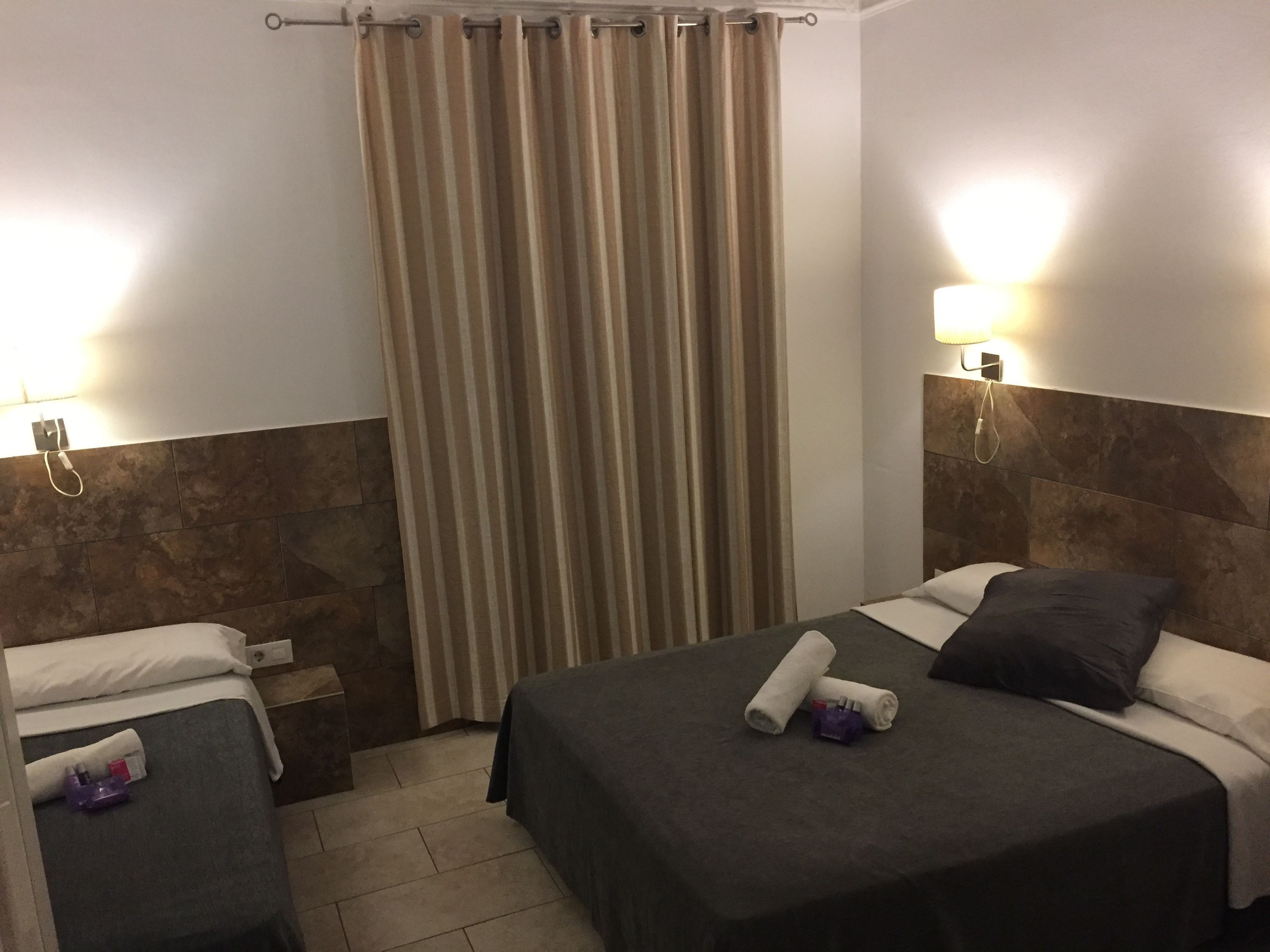 Habitación de hotel con dos camas, una cortina y un teléfono instalado en la pared.