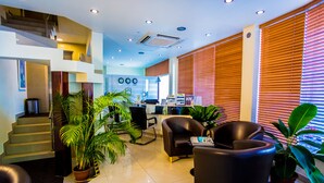 A modern hotel lobby with a staircase, seating area, and large windows with blinds. - Hotel Octave (Malé)