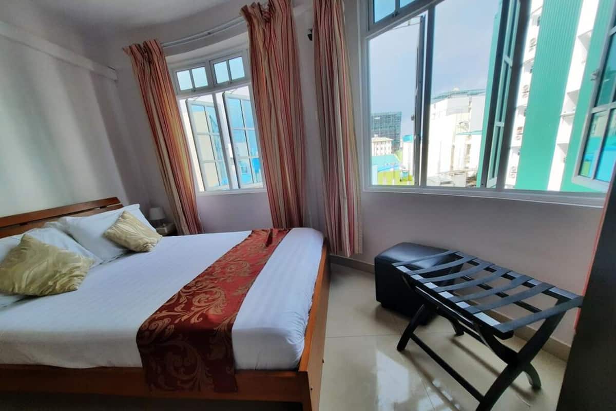 Ein Hotelzimmer mit einem Bett, einer Bank und großen Fenstern.